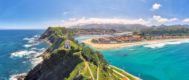 Aerial panorama of a church on top of the cliffs, views of the beach and mountains on the background