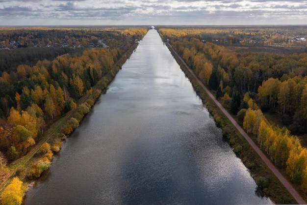 Aerial panoramic view of a long canal leading through a forest in autumn colors Dubna Russia