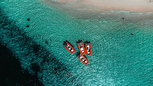 Aerial shot of boats on the sea surrounded by a beach under the sunlight