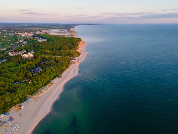 Aerial sunset view of sandy beach, sea and forest on Baltic sea in Yantarny, Kaliningrad region, Russia