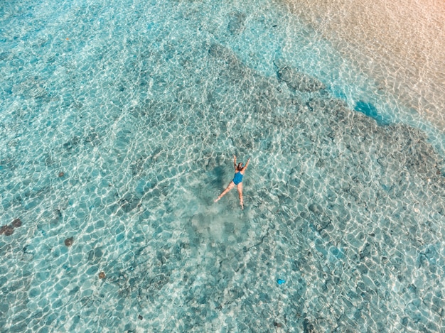 Aerial top down people snorkeling on coral reef tropical caribbean sea, turquoise blue water. Indonesia Wakatobi archipelago, marine national park, tourist diving travel destination