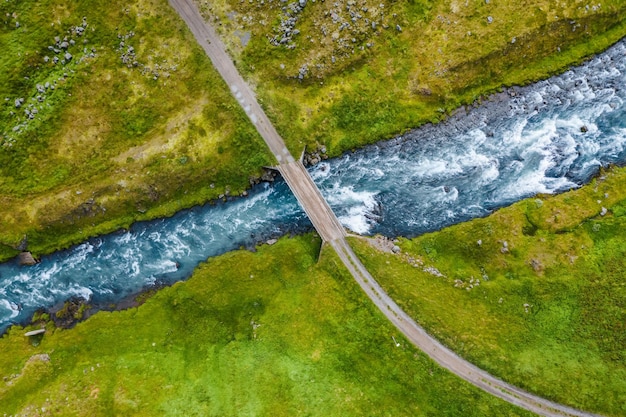 The aerial top down view of a milky blue river and a bridge Iceland