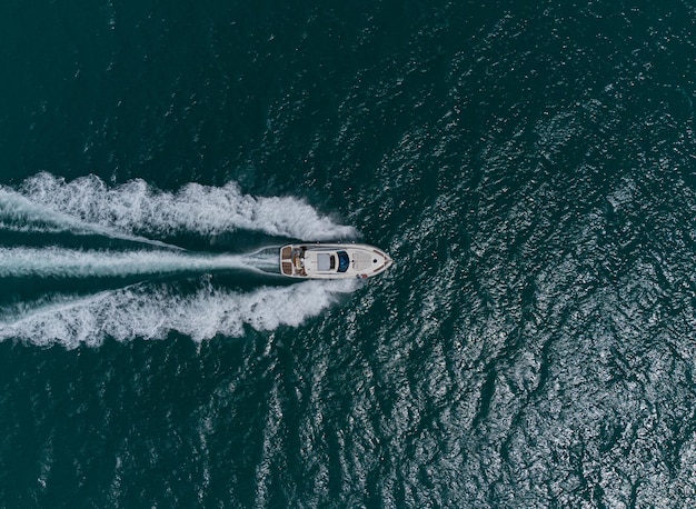 Aerial top down view of speed motor boat on open sea at summer day