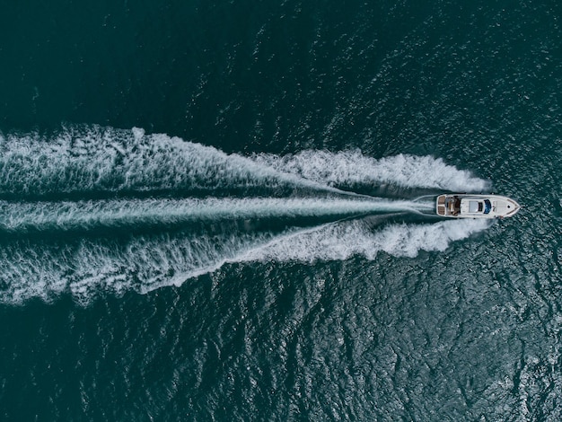 Aerial top down view of speed motor boat on open sea at summer day