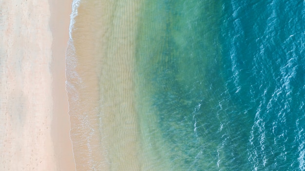 Aerial top view of Beach with shade emerald blue water and wave foam on tropical sea 