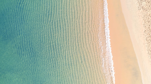 Aerial top view of Beach with shade emerald blue water and wave foam on tropical sea 