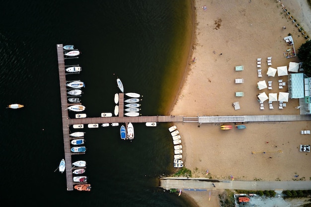 Aerial top view of boats and small jachts near wooden pier at the lake summer entertainment at water