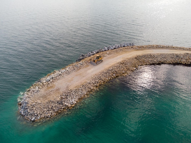 Aerial top view of breakwater construction Bulldozer on a pile of boulders in the sea