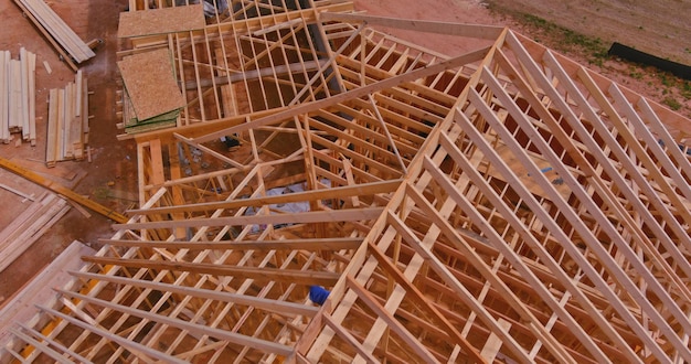 Aerial top view of under construction under framing new wooden roof beams built home with constructi