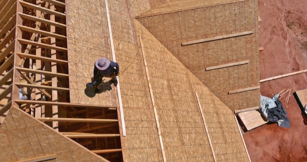 Aerial top view of construction worker nailing roof panels