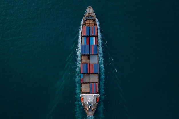 Aerial top view of container ship transporting goods sailing top speed across ocean freight in import export international Worldwide,