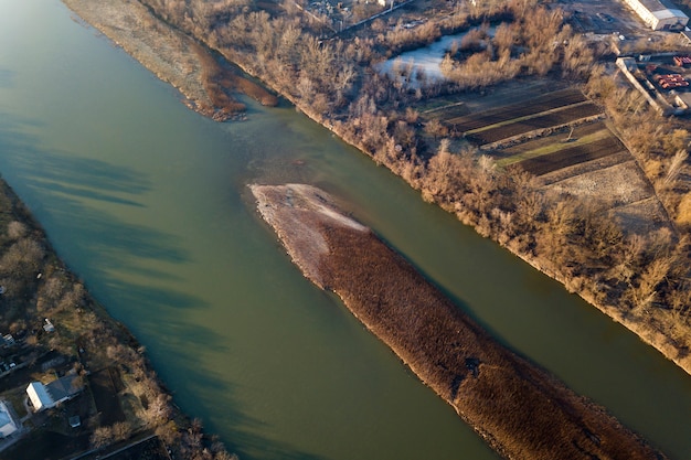 Photo aerial top view, countryside panorama of small island with dry grass in quiet river on sunny day. drone photography.