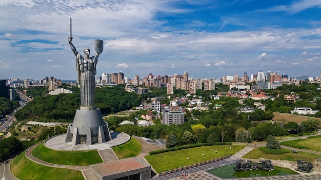 Aerial top view of Kiev Motherland statue monument on hills from above and cityscape, Kyiv city, Ukraine