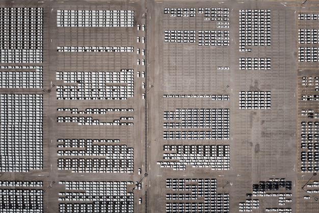 Aerial top view new cars lined up in the port for import export business logistic and transportation by ship in the open sea