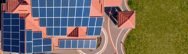 Aerial top view of new modern residential house cottage with blue panels. Renewable ecological green energy production concept