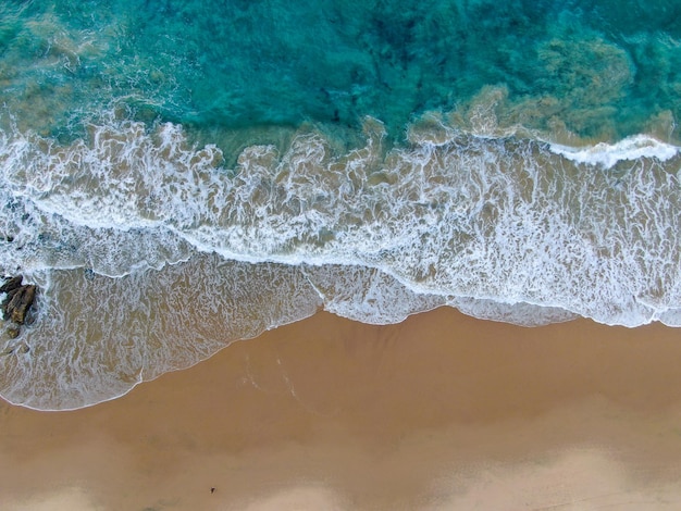 Aerial top view of the ocean colorful waves washing on the coast of the Pacific ocean California