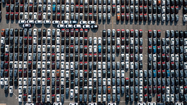 Aerial top view rows of new cars parked in distribution center on car factory Automobile and automotive car parking lot for commercial business industry to dealership for sale