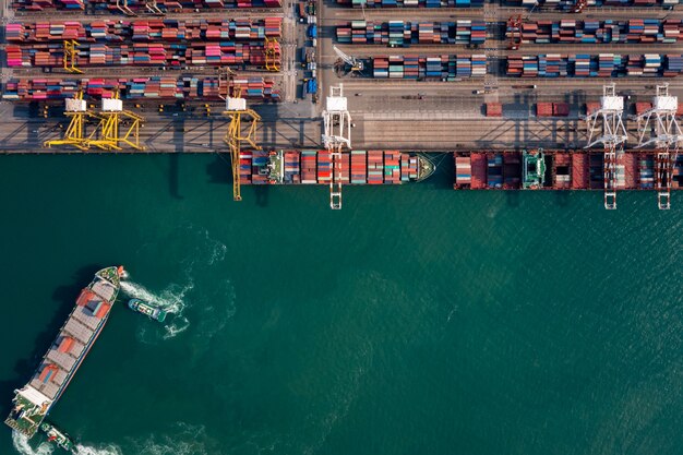 Aerial top view shipping port for international import  export cargo logistics transportation business services and industry  and small tugboat drag container ship