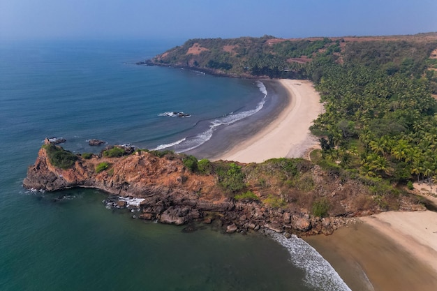 Aerial top view on tropical beach with green palm trees under sunlight Drone view in Goa