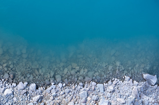 Aerial top view of turquoise lake and rocks abstract background at Tekapo, New Zealand