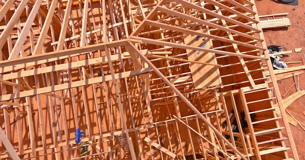 Aerial top view of wooden structure roof truss frame installation by under the construction house