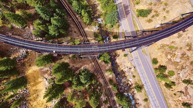 Aerial of train tracks crossing over tracks and road in desert