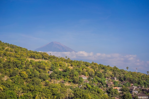 Aerial view of Amed beach in Bali Indonesia Traditional fishing boats called jukung on the black sand beach and Mount Agung volcano in the background partially covered by clouds