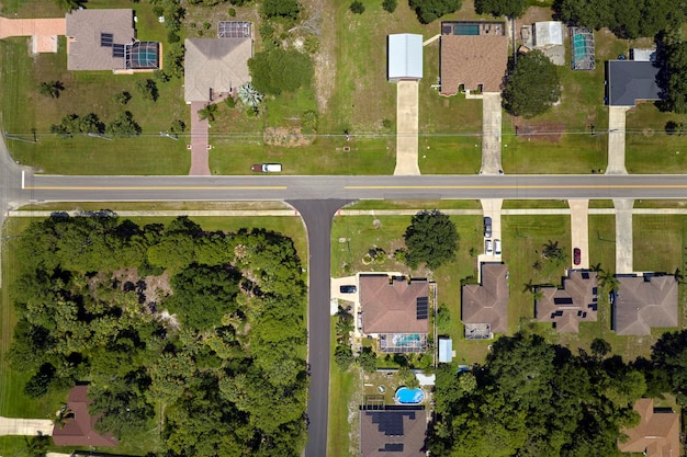 Aerial view of american small town in Florida with private homes between green palm trees and suburban streets in quiet residential area