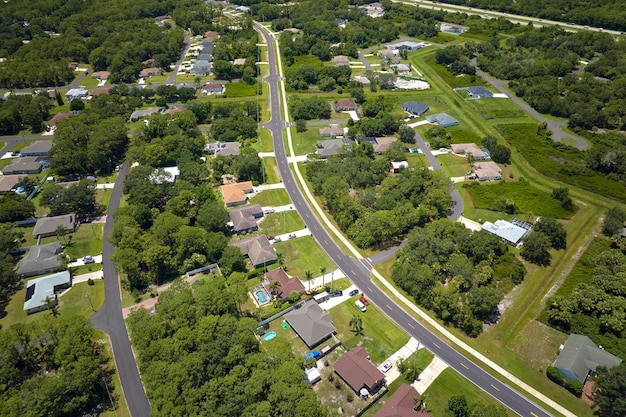 Aerial view of american small town in Florida with private homes between green palm trees and suburban streets in quiet residential area