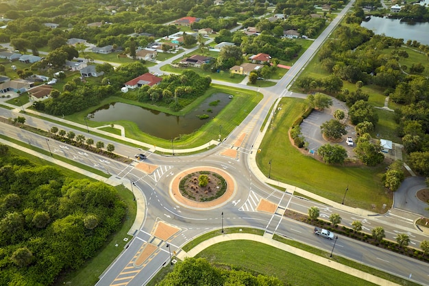 Aerial view of american suburban area with rural road roundabout intersection with moving cars traffic Circular transportation crossroads in Florida