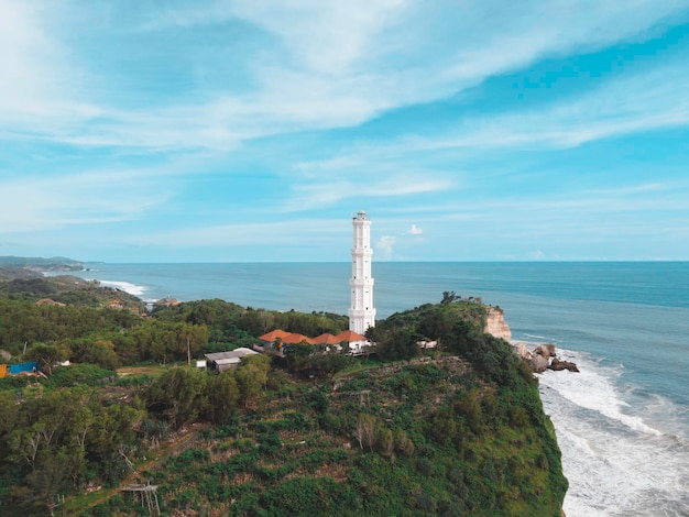 Aerial view of Baron Beach in Gunung Kidul Indonesia with lighthouse and traditional boat