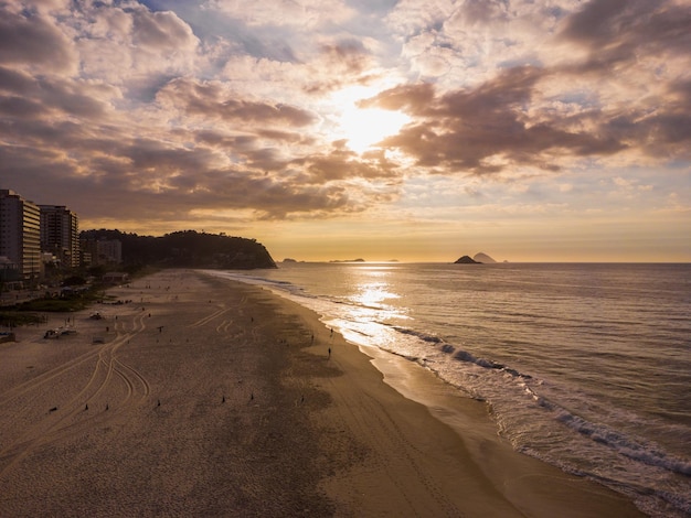 Aerial view of Barra da Tijuca Beach, a paradise in the west side of Rio de Janeiro, Brazil. Big hills around like Pedra da GÃÂ¡vea. Sunny day with some clouds at dawn. Greenish sea. Drone Photo.