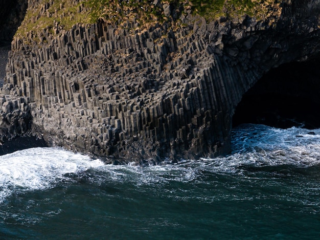 Photo aerial view of basalt columns and crashing waves at reynisfjara black sand beach iceland