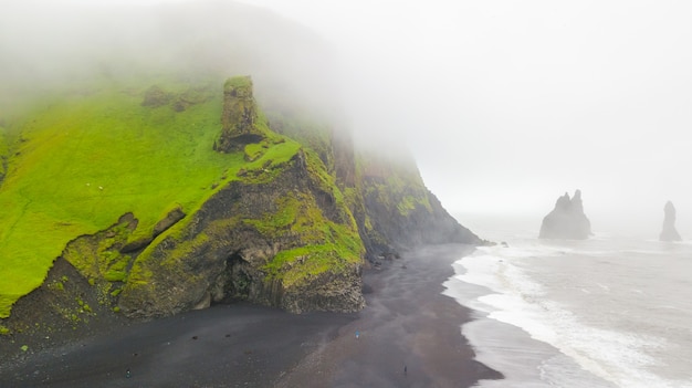 Aerial view of beautiful Famous Reynisdrangar rock formations at black Reynisfjara Beach.