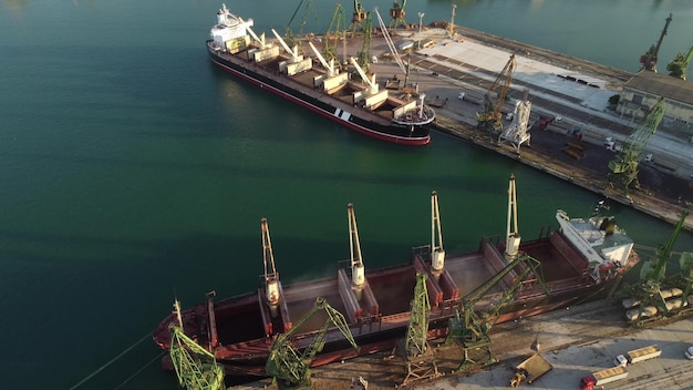 Aerial view of big cargo ship bulk carrier is loaded with grain of wheat in port at sunset