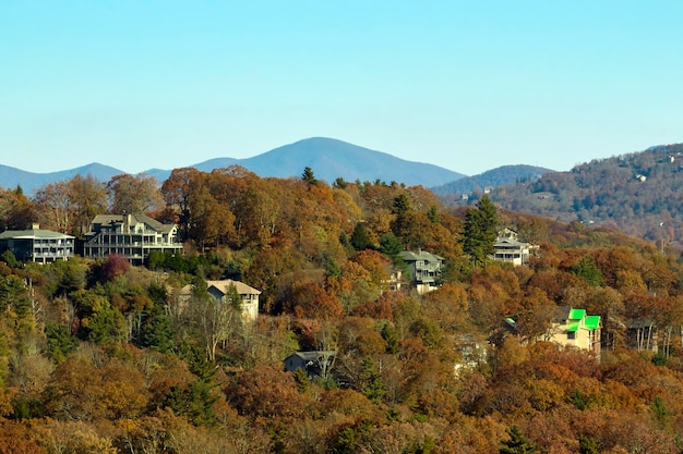 Aerial view of big family houses on mountain top between yellow trees in North Carolina suburban area in fall season Real estate development in american suburbs