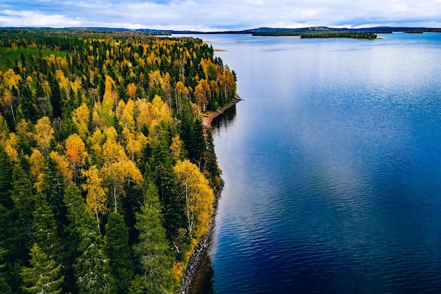 Aerial view of blue lake with reflection fall forest with autumn colorful trees in Finland