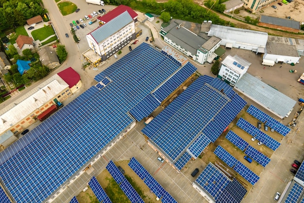 Aerial view of blue photovoltaic solar panels mounted on industrial building roof for producing clean ecological electricity. Production of renewable energy concept.