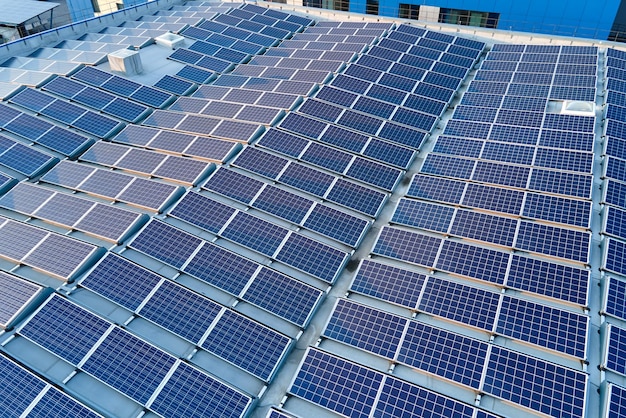 Aerial view of blue photovoltaic solar panels mounted on industrial building roof for producing green ecological electricity Production of sustainable energy concept