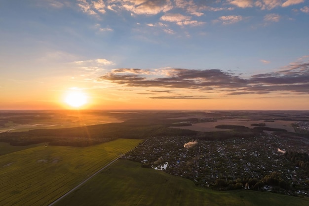 Aerial view on blue red sky background with evening fluffy curly rolling clouds with setting sun over village