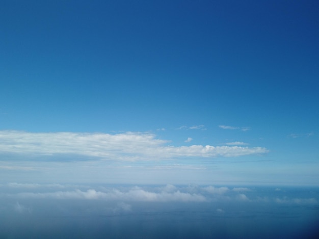 Aerial view blue sky sun and fog over calm sea the drone flies over foggy and fluffy clouds abstract