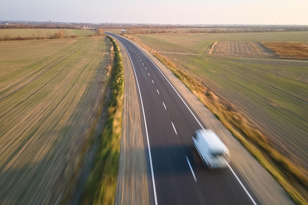 Aerial view of blurred fast moving cargo van driving on highway hauling goods. Delivery transportation and logistics concept.