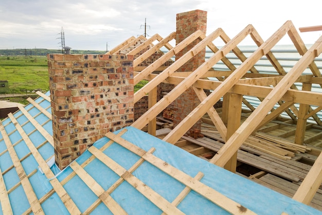 Aerial view of a brick house with wooden roof frame under construction