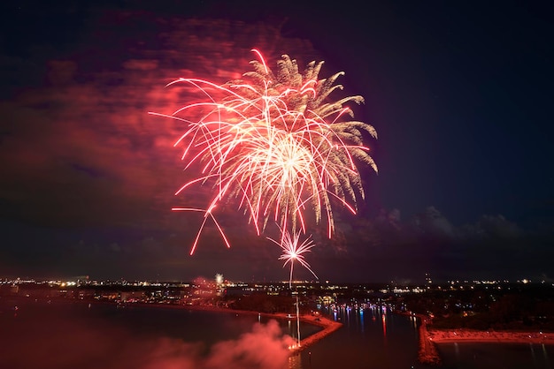 Aerial view of bright fireworks exploding with colorful lights over sea shore on US Independence day holiday