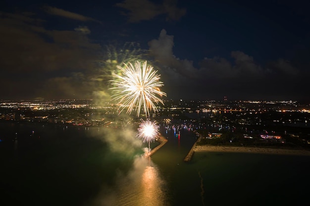 Aerial view of bright fireworks exploding with colorful lights over sea shore on US Independence day holiday