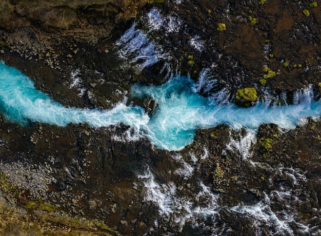 Photo aerial view of bruarfoss waterfall icelands bluest waterfall with vibrant blue water flowing over stones most famous place in iceland