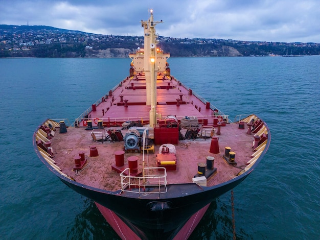 Aerial view of a bulk carrier at evening showcases a stunning display of lights reflecting off the water as the massive vessel cuts through the waves