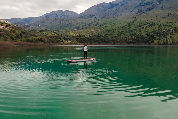 Aerial view by drone of a woman practicing Stand Up Paddle or SUP on lake