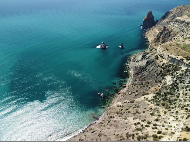 Aerial view on calm azure sea and volcanic rocky shores small waves on water surface in motion blur