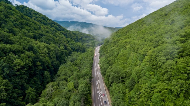 Aerial view of car driving along the winding mountain pass road through the forest in Sochi Russia